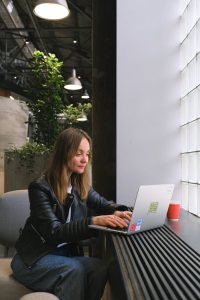 Woman freelancer using laptop indoors in a stylish office setting with natural light.